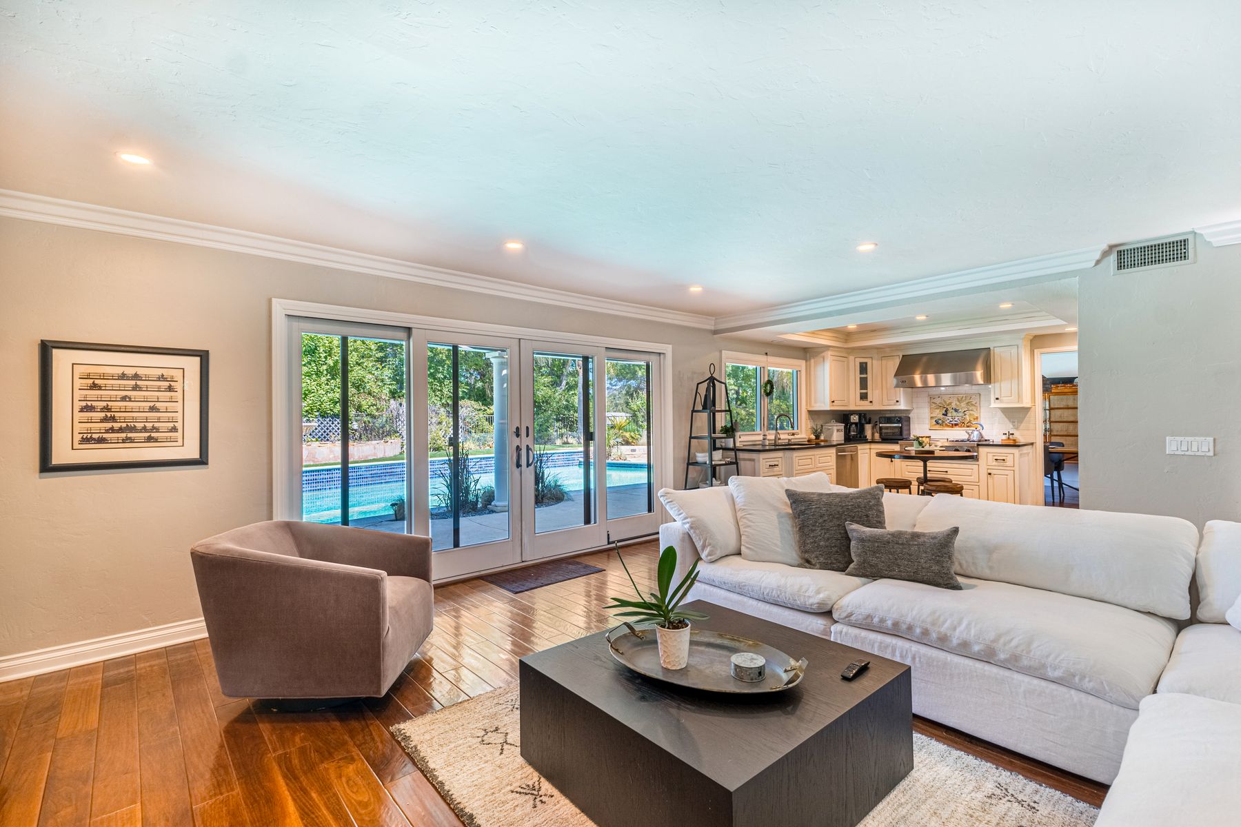 Living room with full height glazed doors facing a garden and pool.